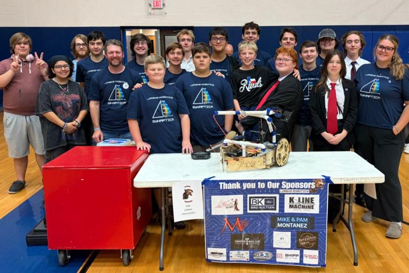 Group of students standing behind a table with a robot on it