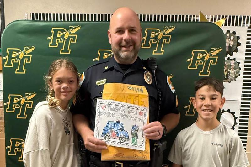 Fifth-graders Hannah Divens and Hudson Dobo present cards to Sgt. Robert Broom of the Penn Township Police