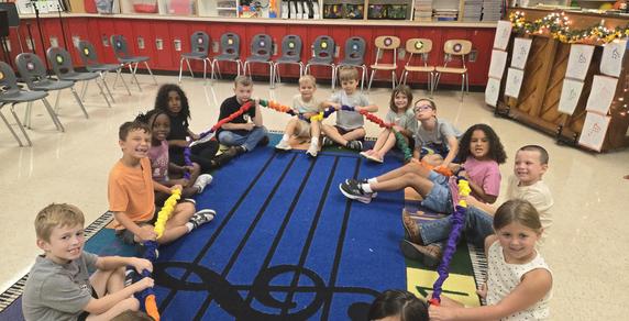 Group of children sitting on a colorful rug, engaging in an interactive activity.