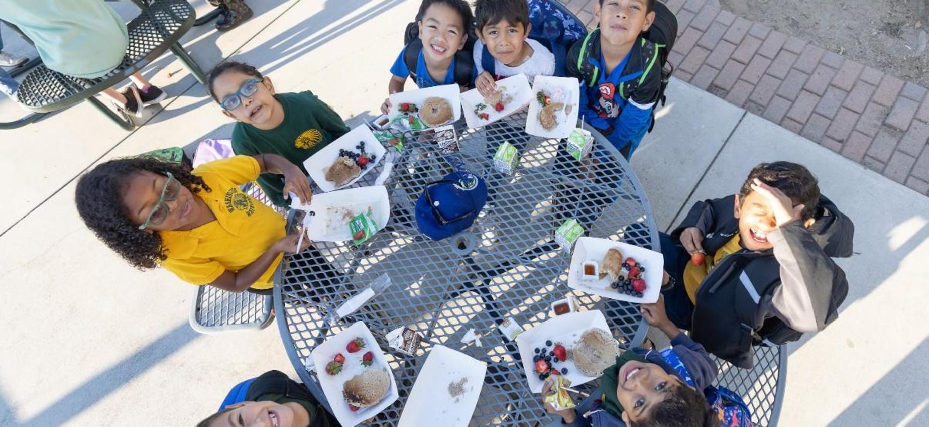 Group of children enjoying lunch together at a picnic table.