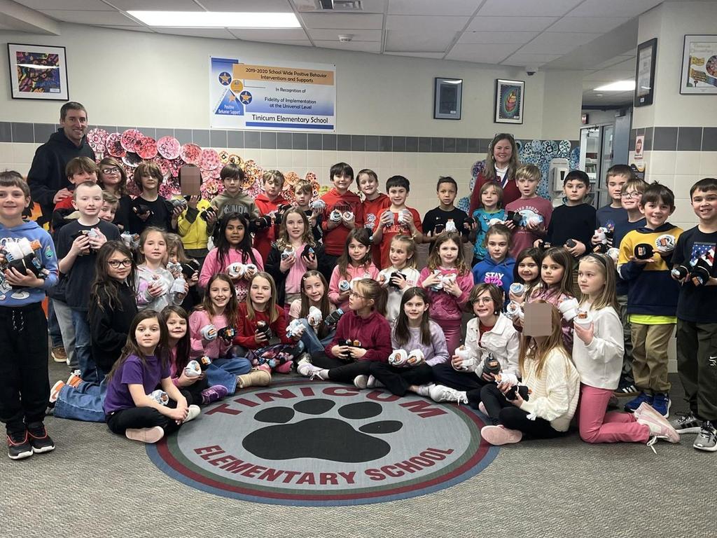 Group of students in the school hallway standing in front of the Tinicum Elementary School rug.