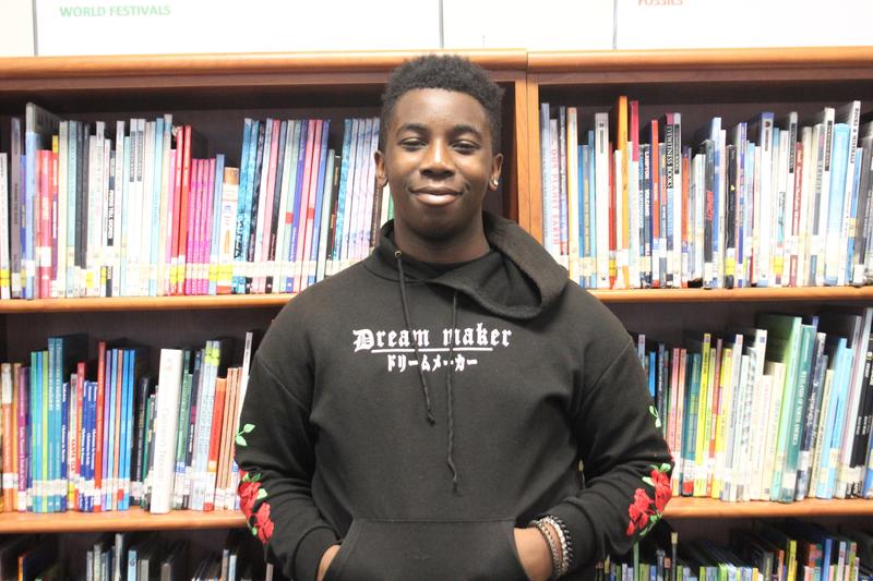 Ji'Quan standing in front of bookcase.
