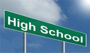 Green road sign displaying 'High School' against a blue sky.