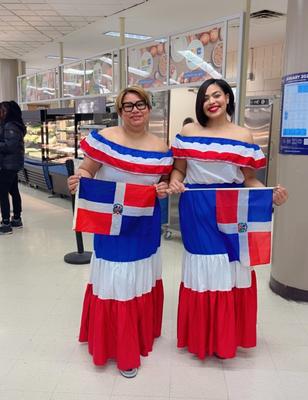 Two women in traditional Dominican attire holding flags.