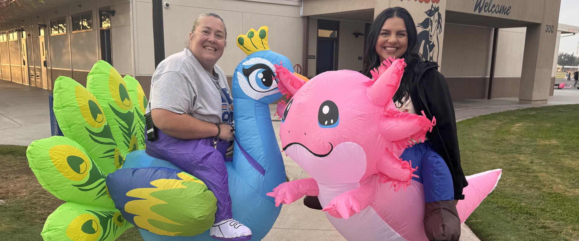Two people in inflatable costumes, one a peacock and the other a pink creature.