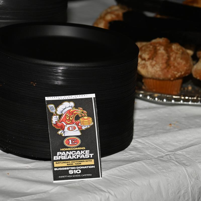 Black plates stacked beside a sign for a pancake breakfast event.