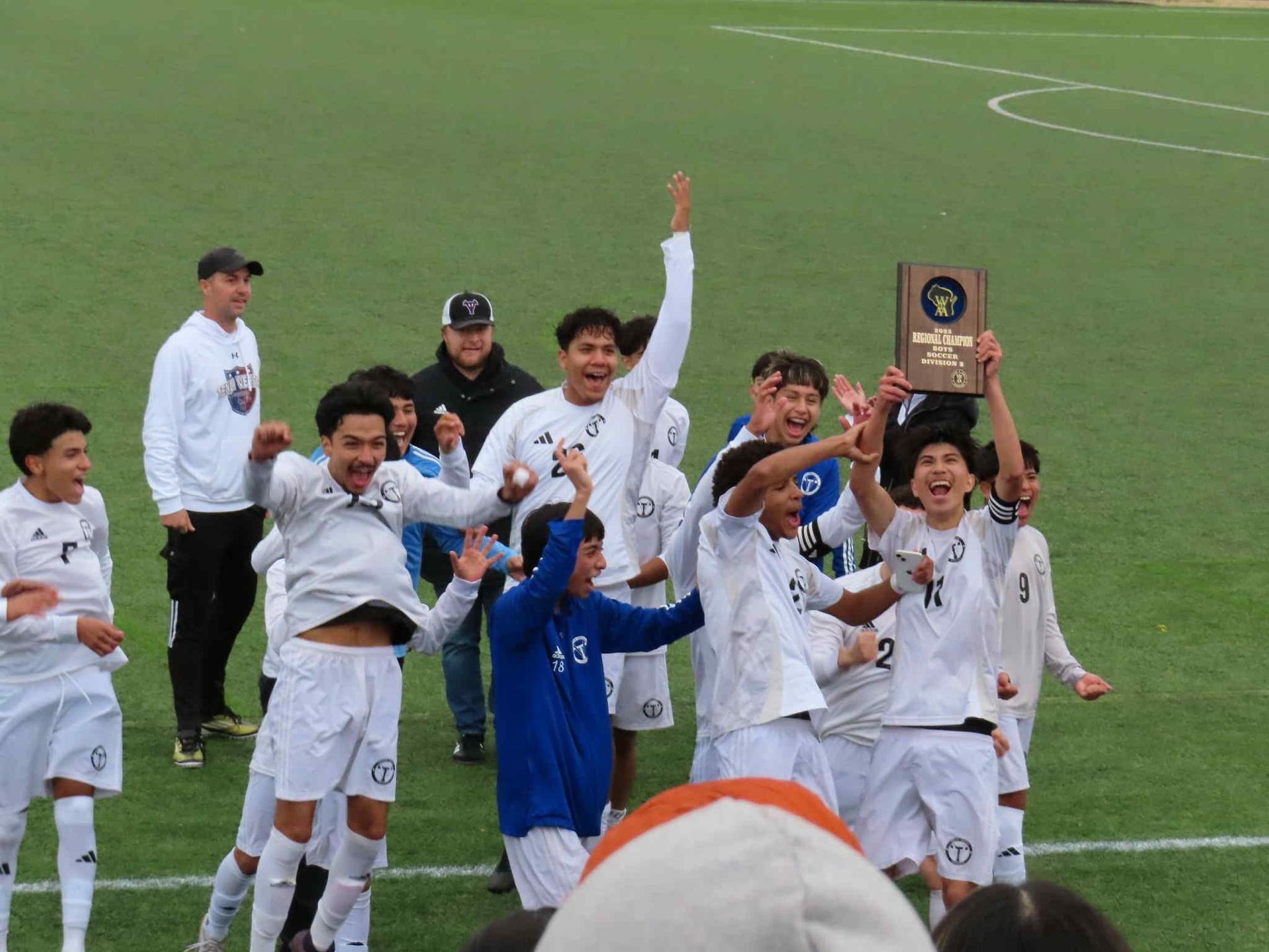 The soccer team celebrating their regional win on the field after the game.