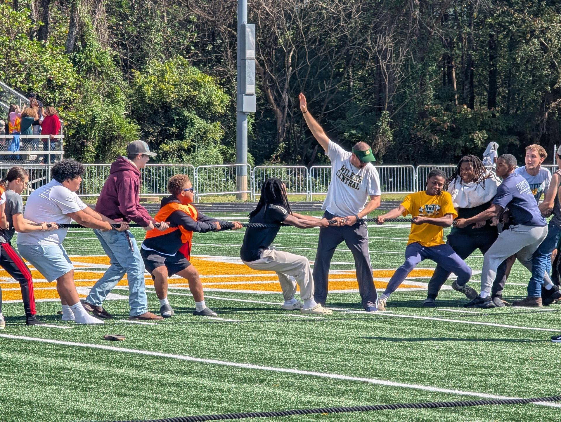 Participants engaged in a tug-of-war on a grassy field.