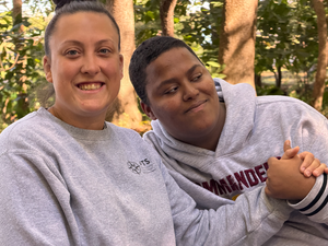 staff and student hold hands while smiling at camera