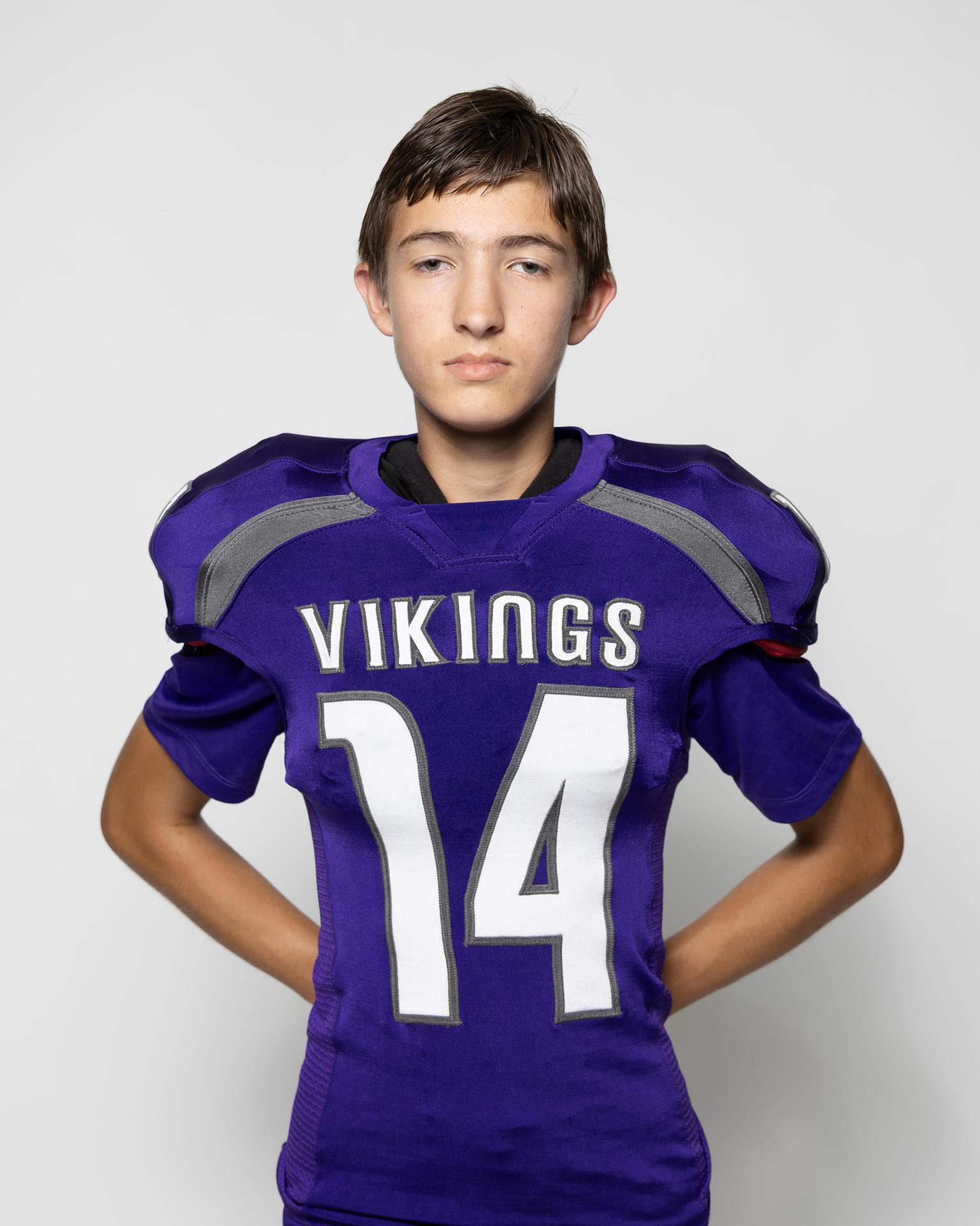 Young athlete in a purple football jersey with the number 14, standing confidently.