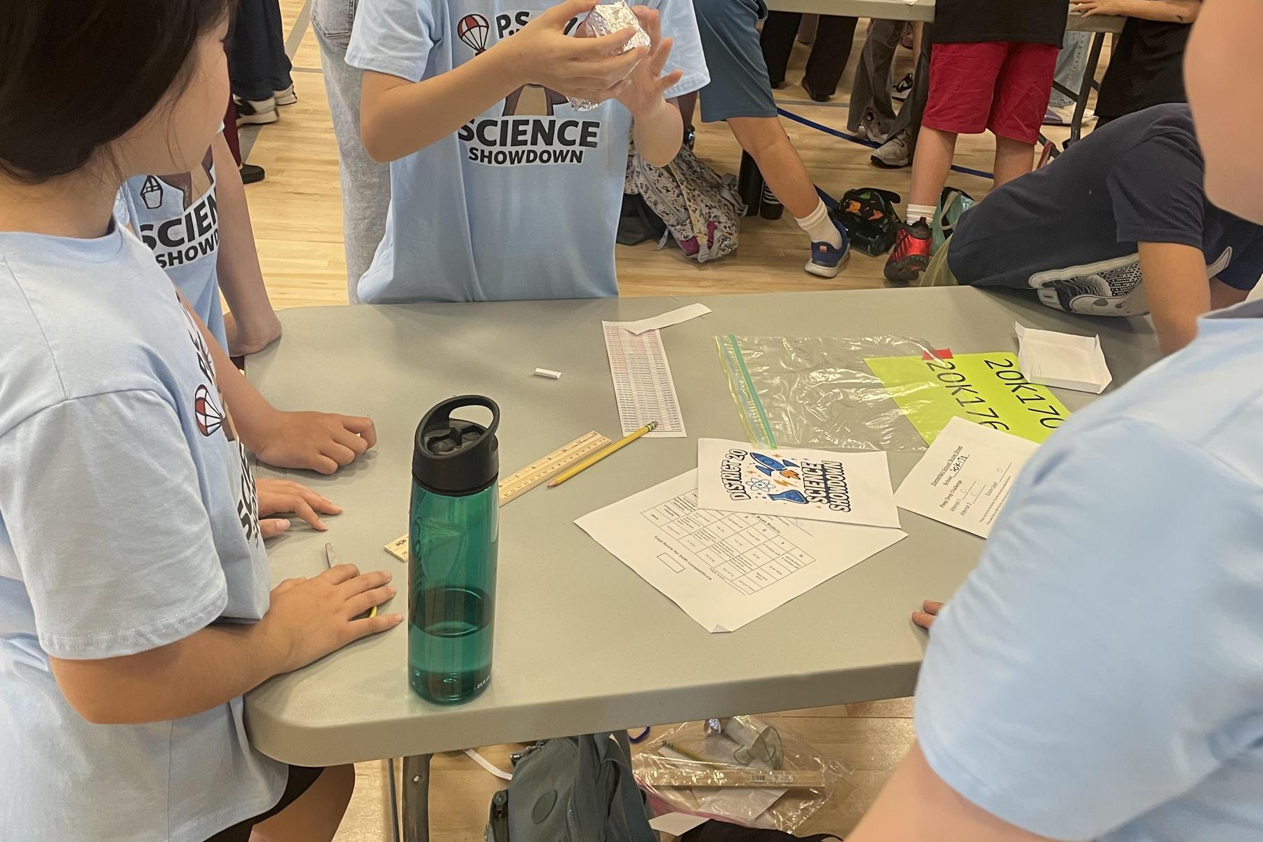 Students collaborating on a science project at a table.
