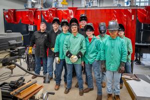 students in welding gear standing in lab