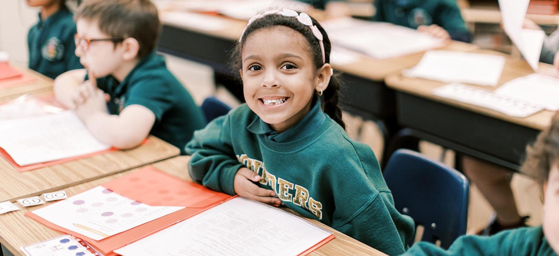 Smiling elementary student works at her desk