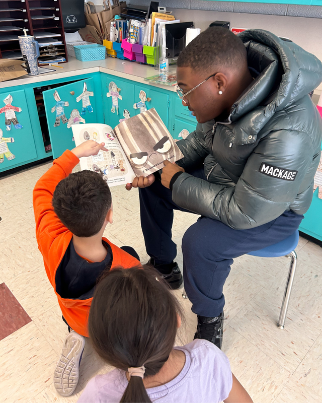HS student reading to younger child