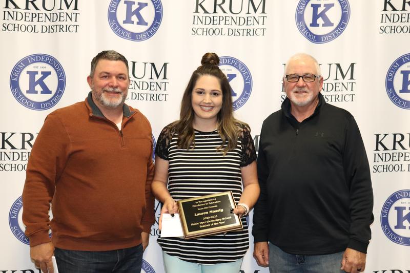 lauren mosely stands with board president eric borchardt and board vp terry knight as they present her with her teacher of the year plaque