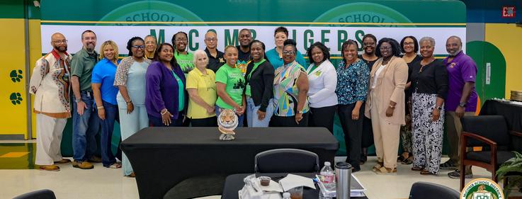 Group photo of a diverse team of educators posed together in a school setting.