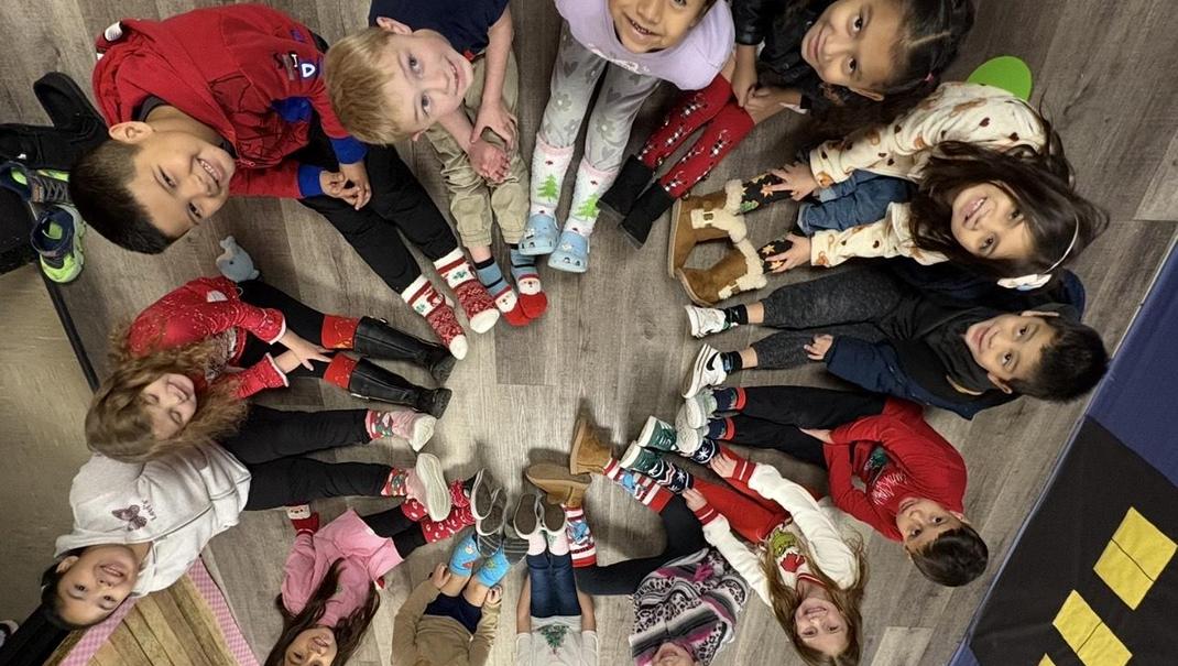 Children sitting in a circle wearing colorful socks, smiling and playing.