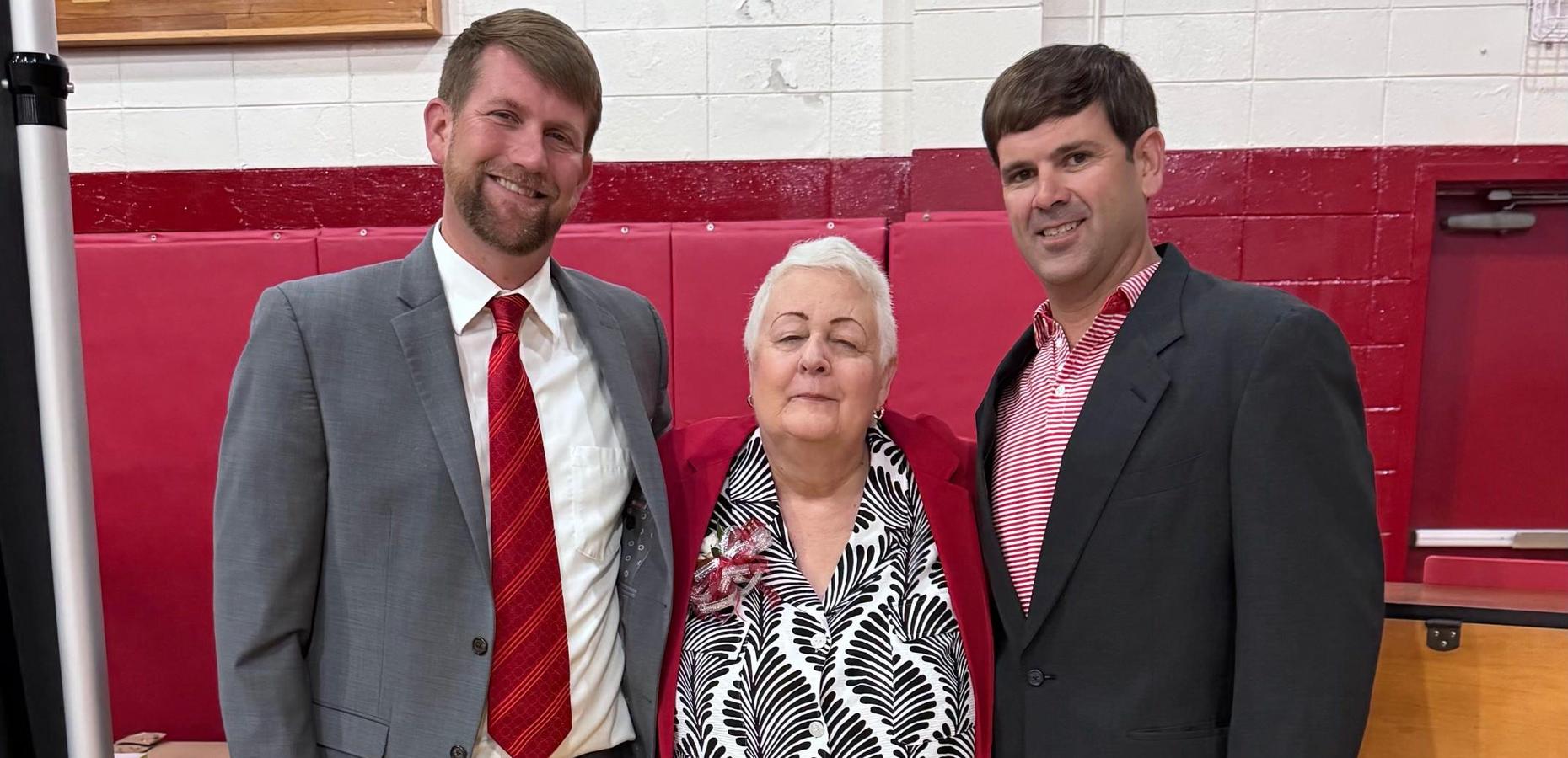 Three adults posing together at a formal gathering.
