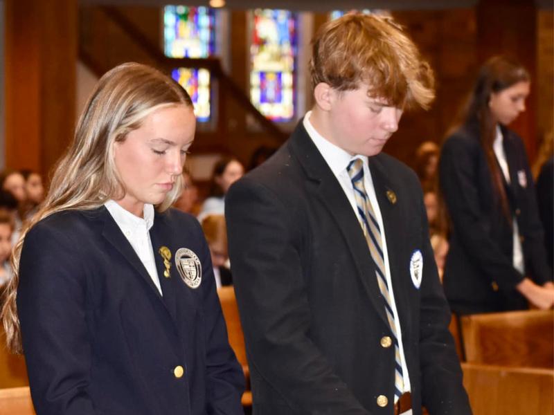 students praying in mass in church