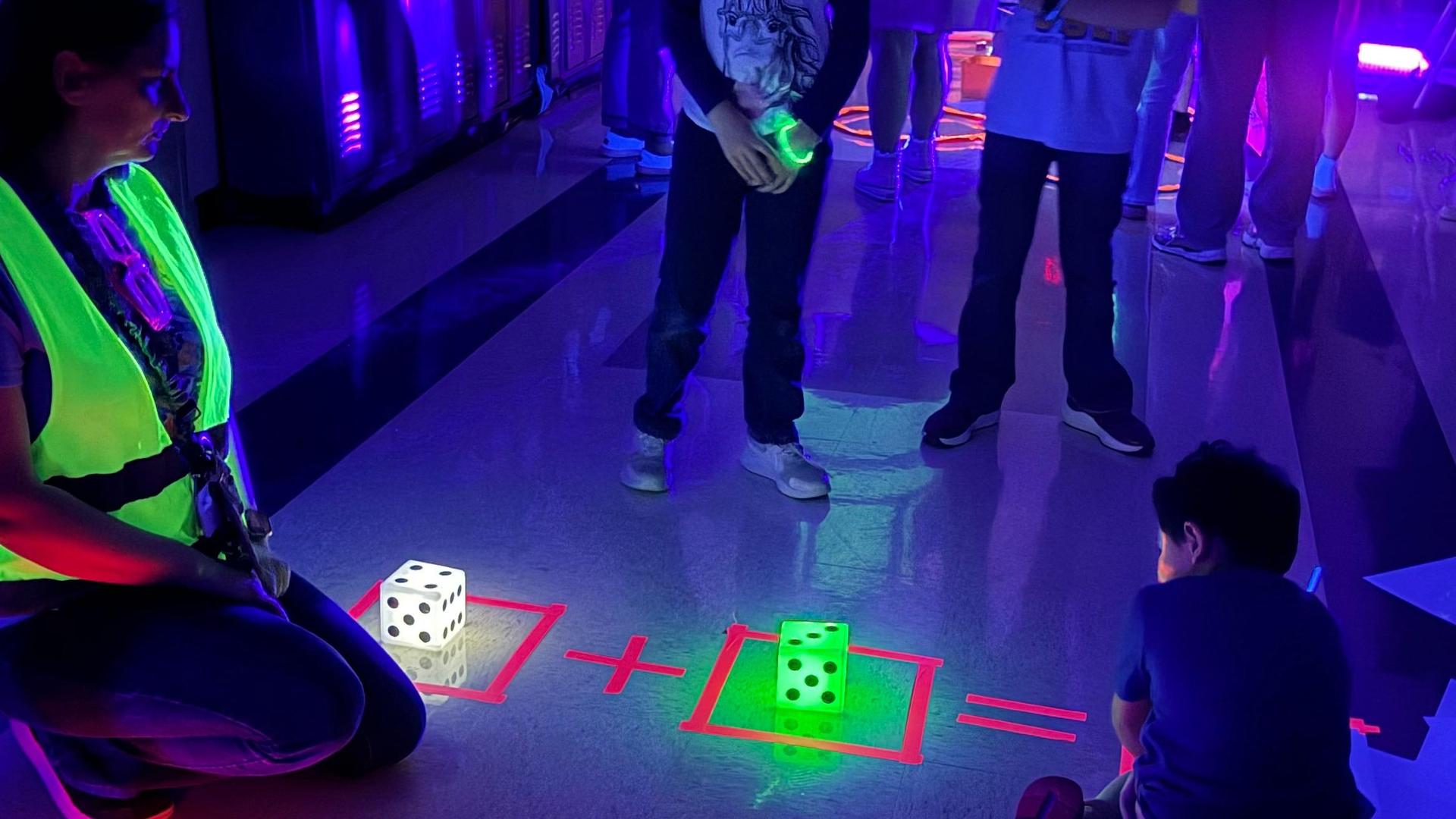 Group of children playing with glowing dice in a dark room.