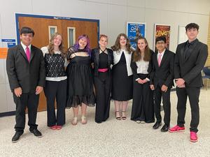 Another FHS state bound choir ensemble standing around in choir hall.
