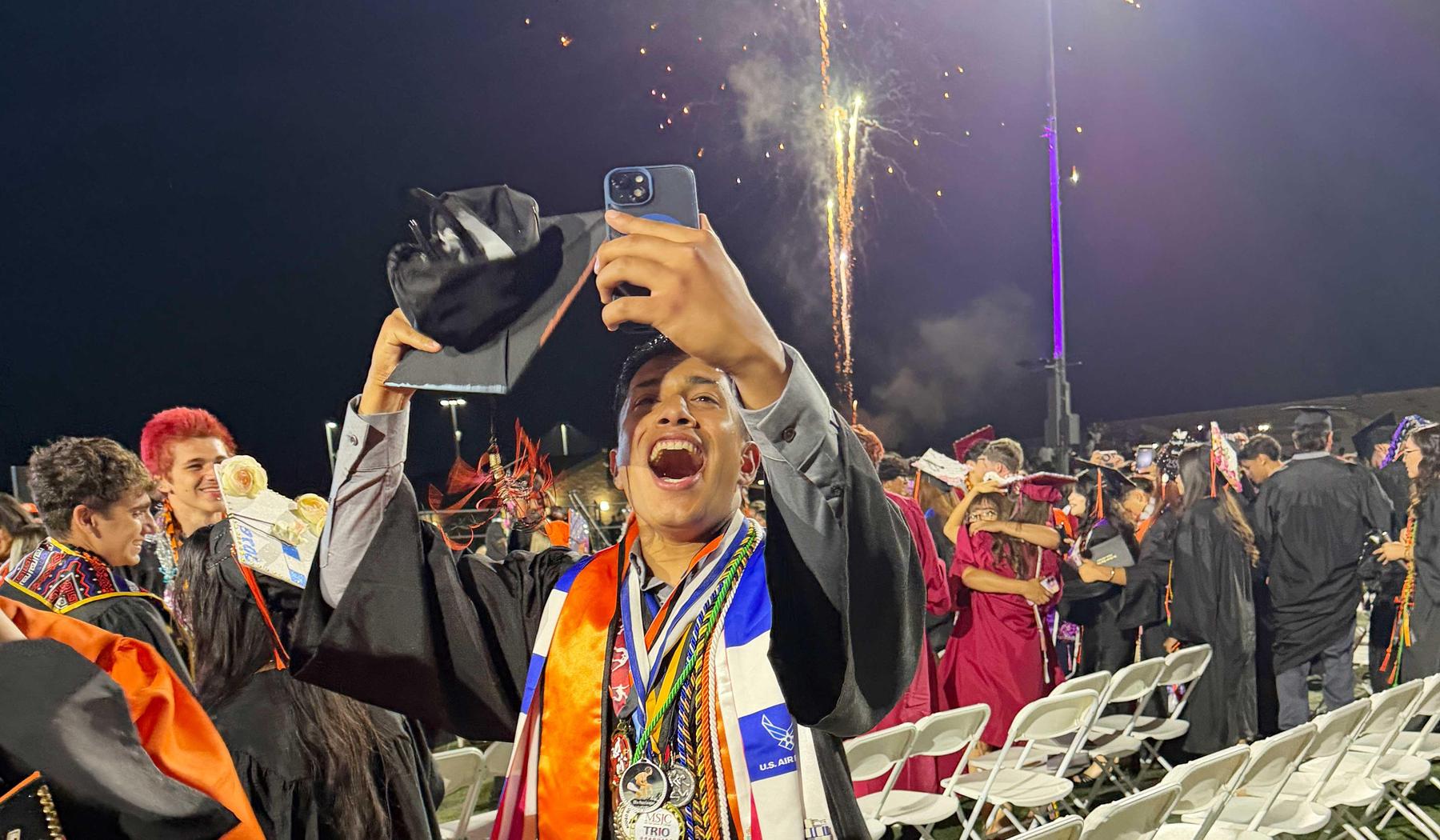 SJHS graduate shouting with excitement with fireworks in the background