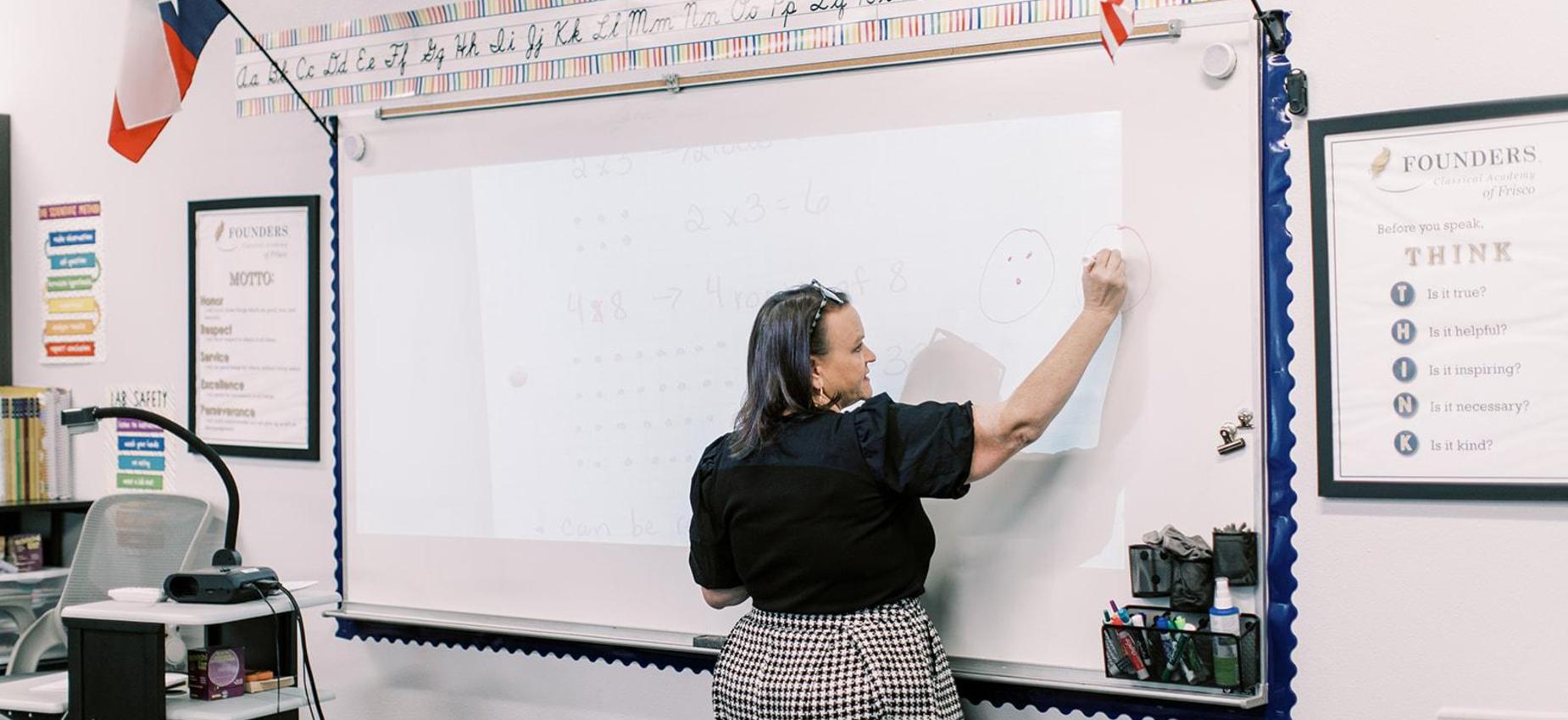 Teacher writes on the whiteboard during a lesson