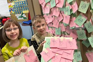 First-graders Emma Rose Pierce and Luca Gambone hold Grinches and Cindy Lou Whos to place on classroom doors