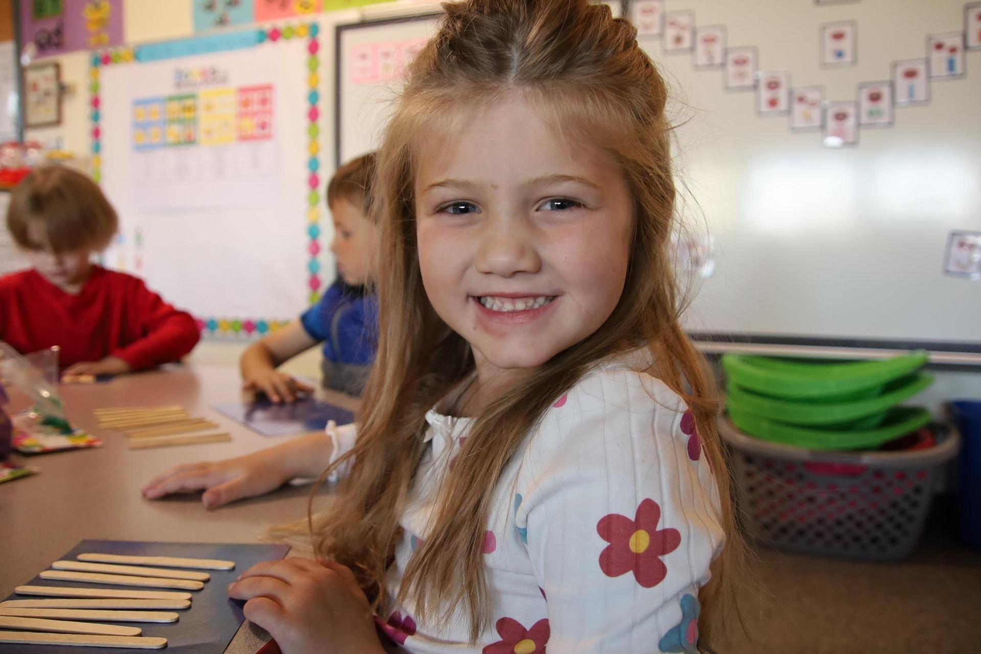 elementary school girl smiling at the camera in a classroom