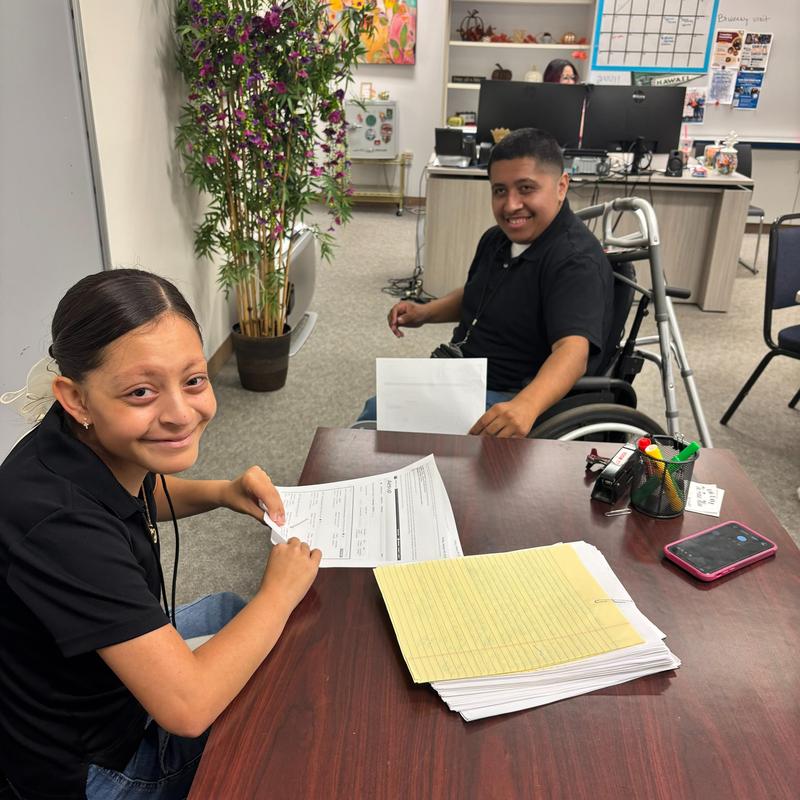 two students at desk sitting with papers on top