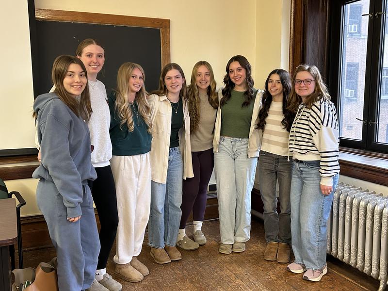 group of high school girls with arms around each other in front of a chalkboard