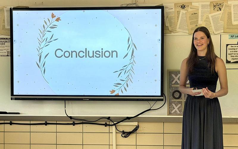Presentation with a woman standing beside a screen displaying 'Conclusion'.