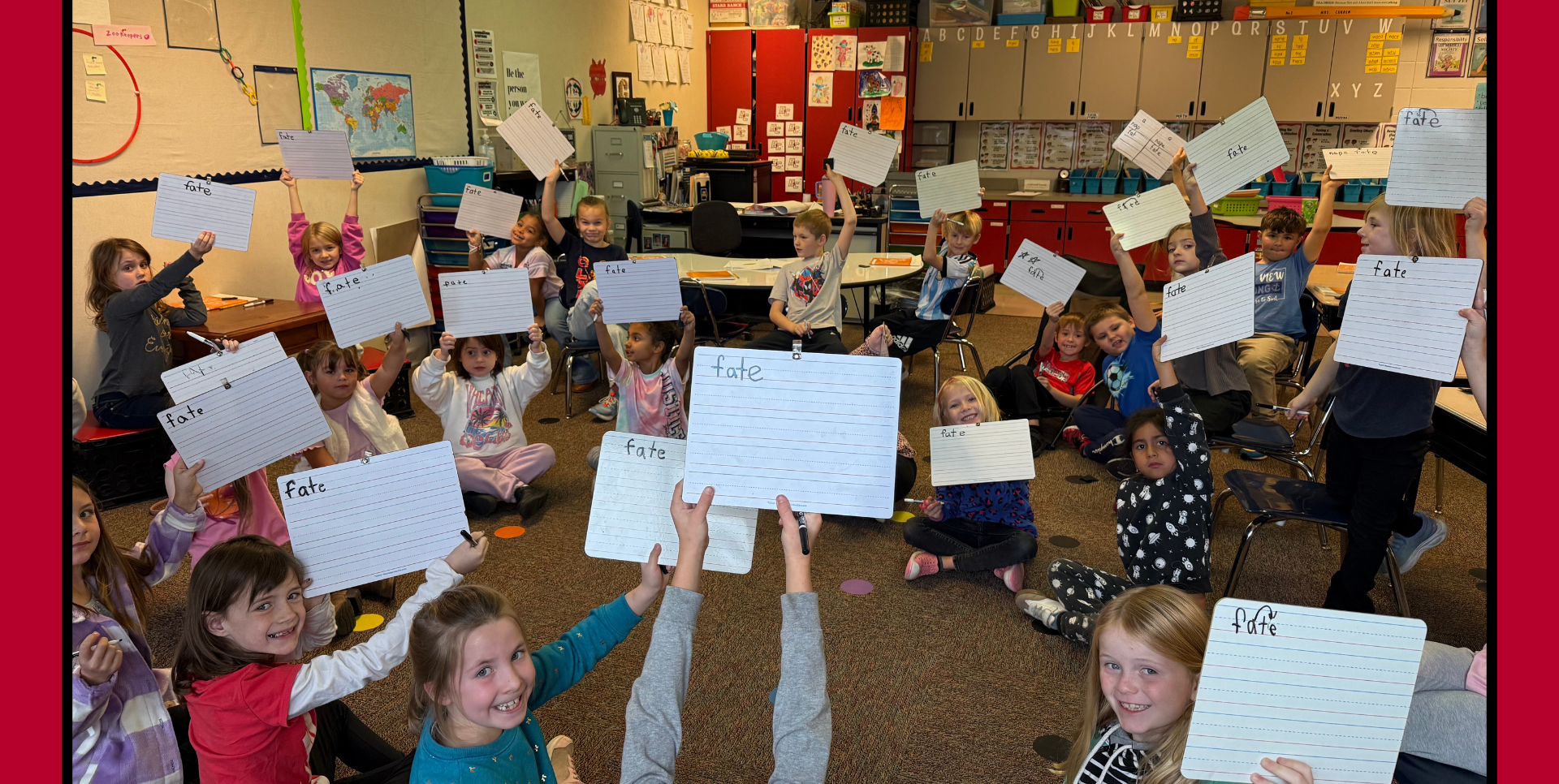 Students in a classroom holding up whiteboards with words written on them.
