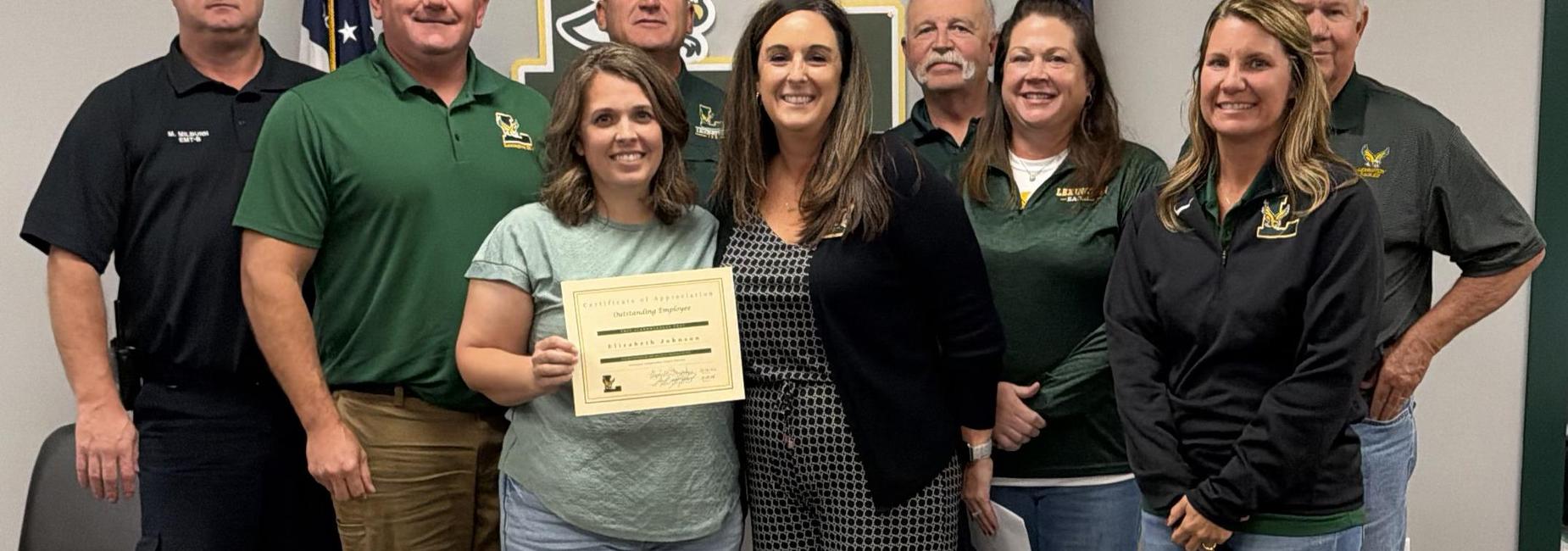 Group of people posing for a photo with a certificate presentation.