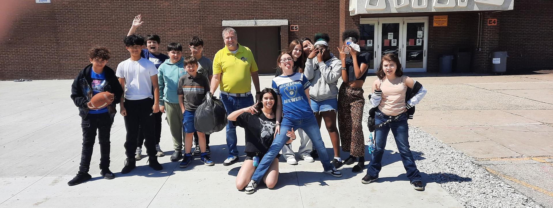 Group of children and adults posing together outside a building.