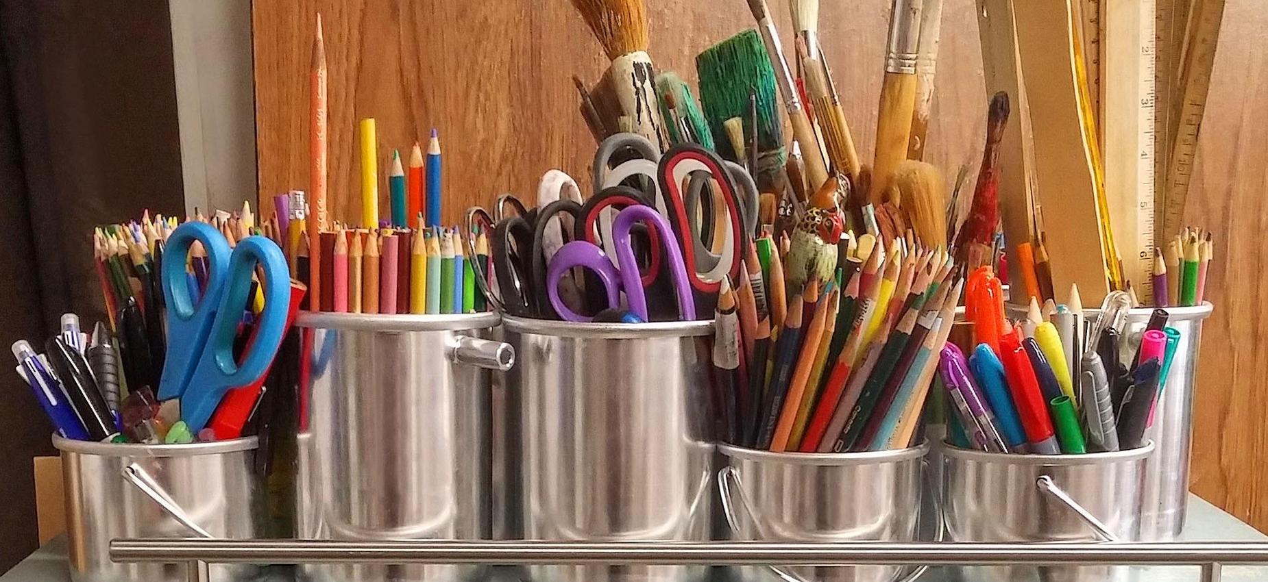 Colorful art supplies organized in metal containers on a table.