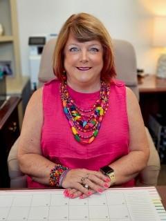 Picture of Interim Superintendent Nancy Barbour. She is smiling at her desk.