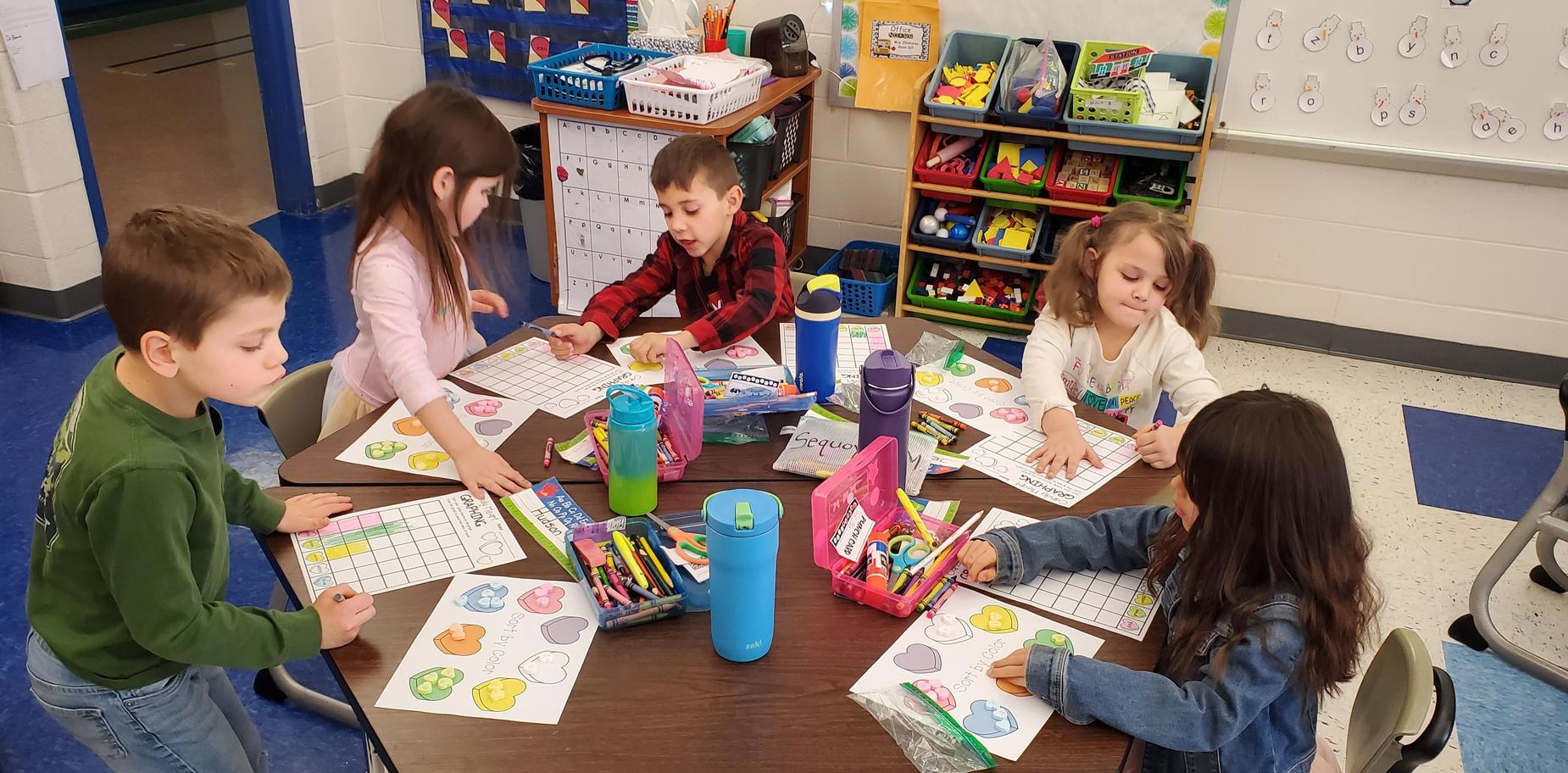 students actively working at table on counting hearts