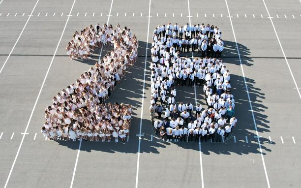 Senior students gathered in the parking lot to form the number 26.