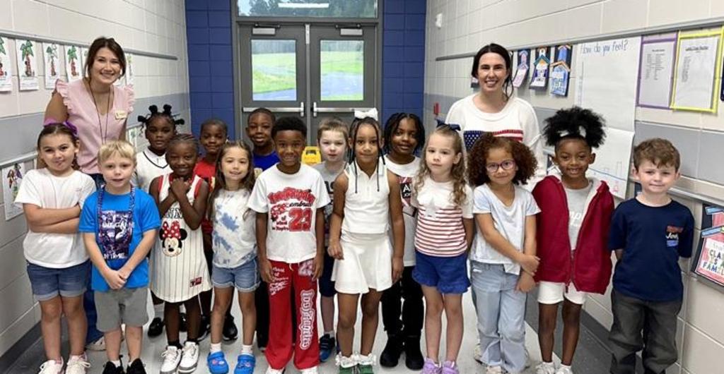 Students and their teachers smiling in the hallway