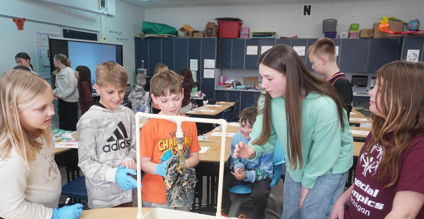 A high school student shows younger students how tobacco use can damage lungs.