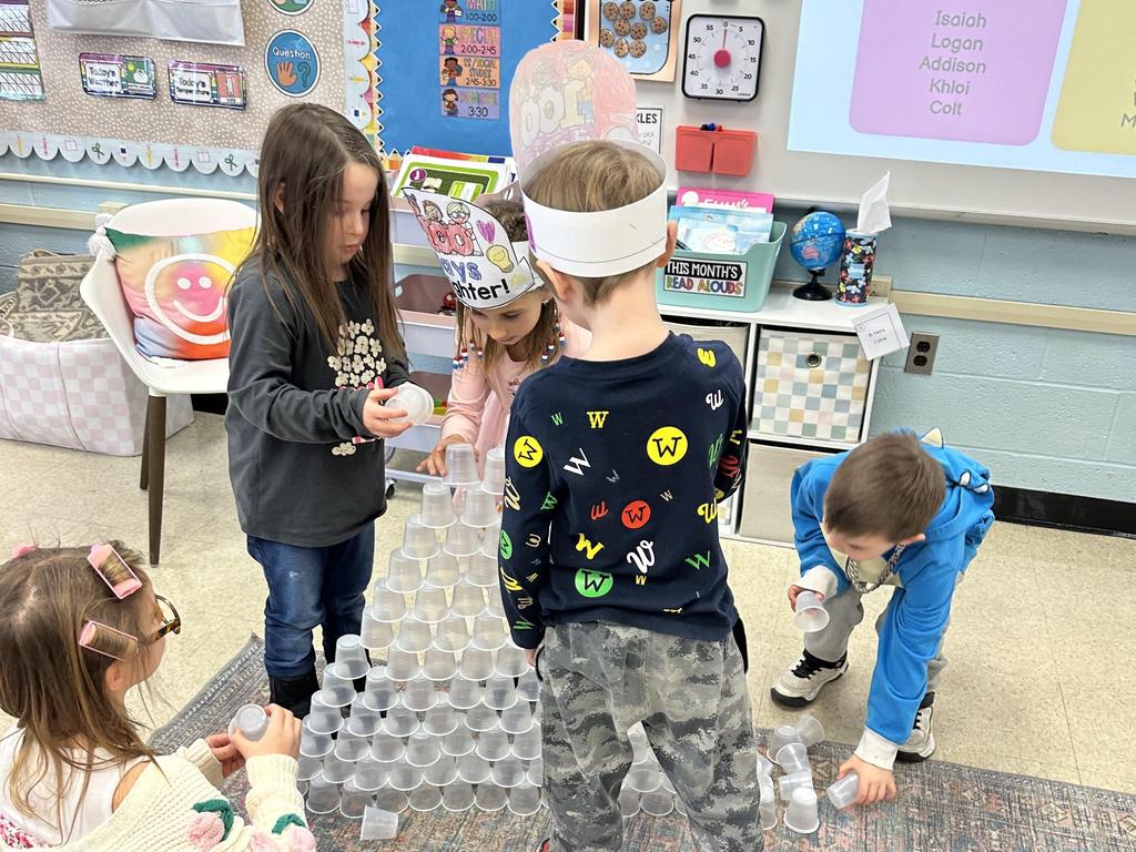 Students stacking plastic cups into a pyramid in the classroom.