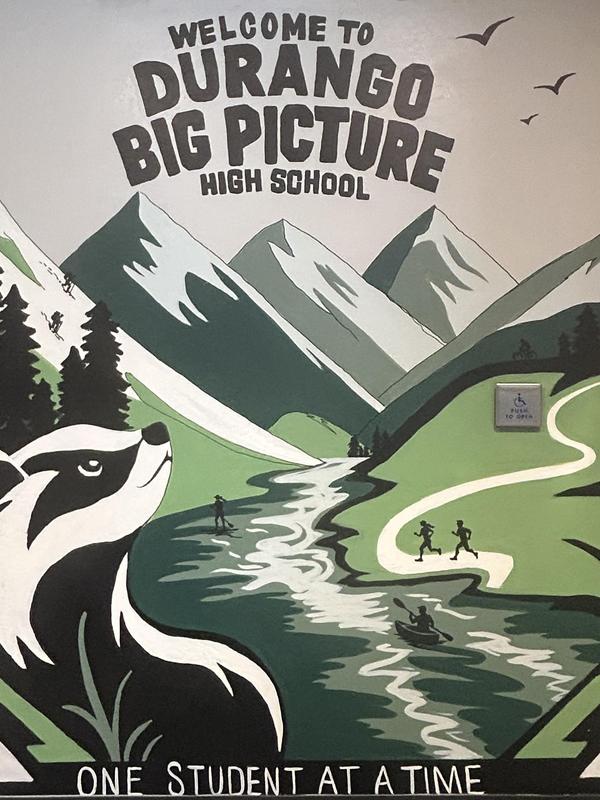 Mural featuring mountains, a river, and a bear with school name and motto.