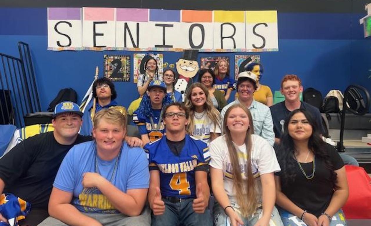 Group of high school seniors in blue and gold clothing posing together with decorations.