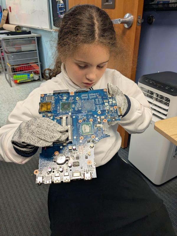 A third grade student looking at a motherboard