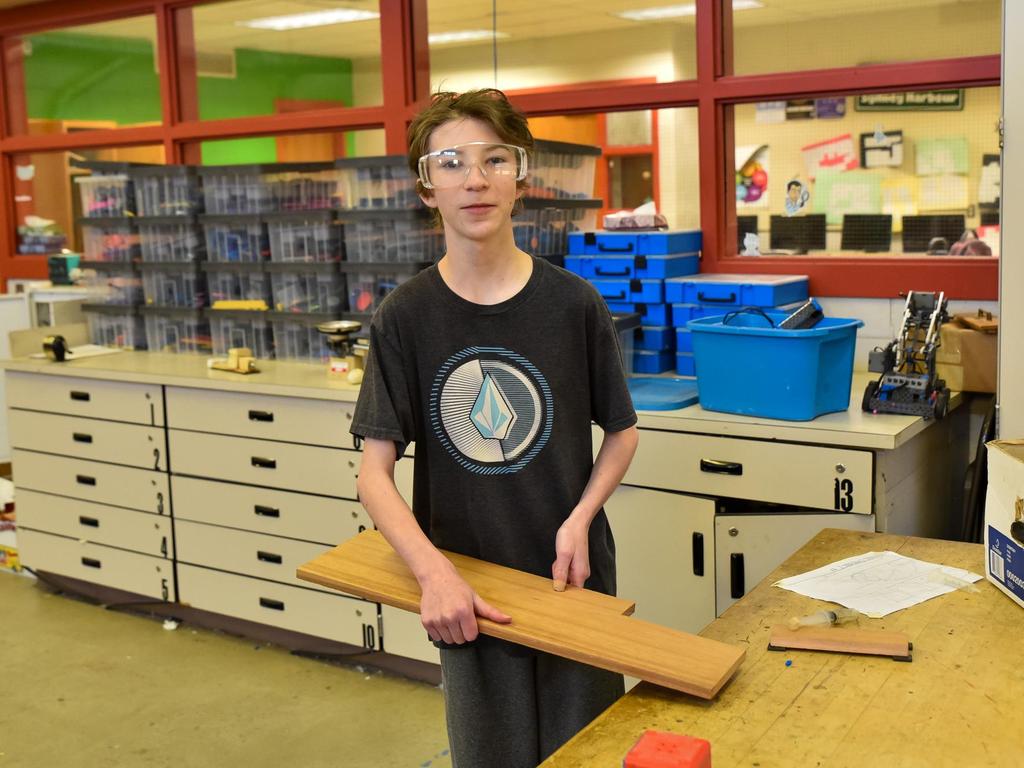 A student wearing safety goggles and holding a board.