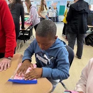 Students in a classroom organizing and folding fabric.