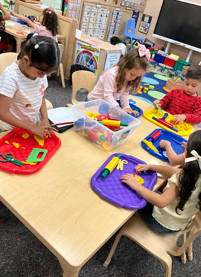 four students playing with playdough