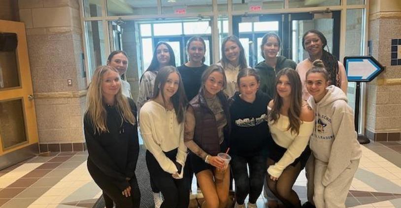 Group of girls posing together in a school lobby.