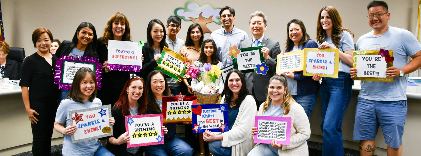 Group of people holding signs with positive messages and flowers in a celebratory setting.